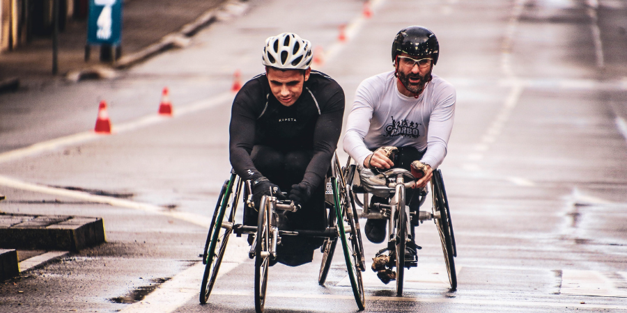 Two men in racing wheelchairs on a city street